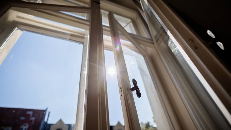 welche-foerderung-bekomme-ich-momentan-beim-fenstertausch-zeigt-hand-mit-miniaturhaus-und-energieeffizienzskala-vor-gruenem-hintergrund.png